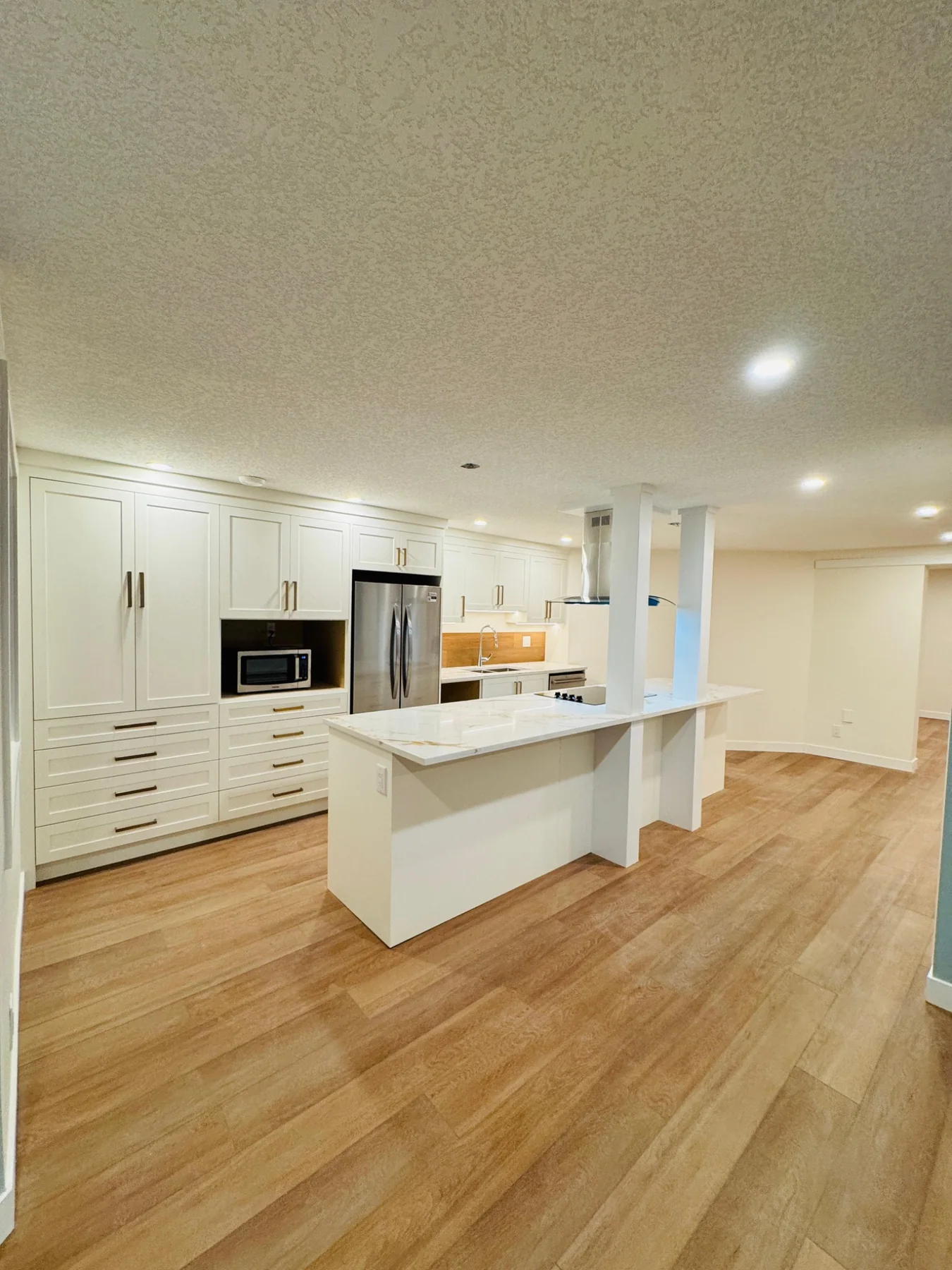Large white kitchen renovation with island and wood flooring